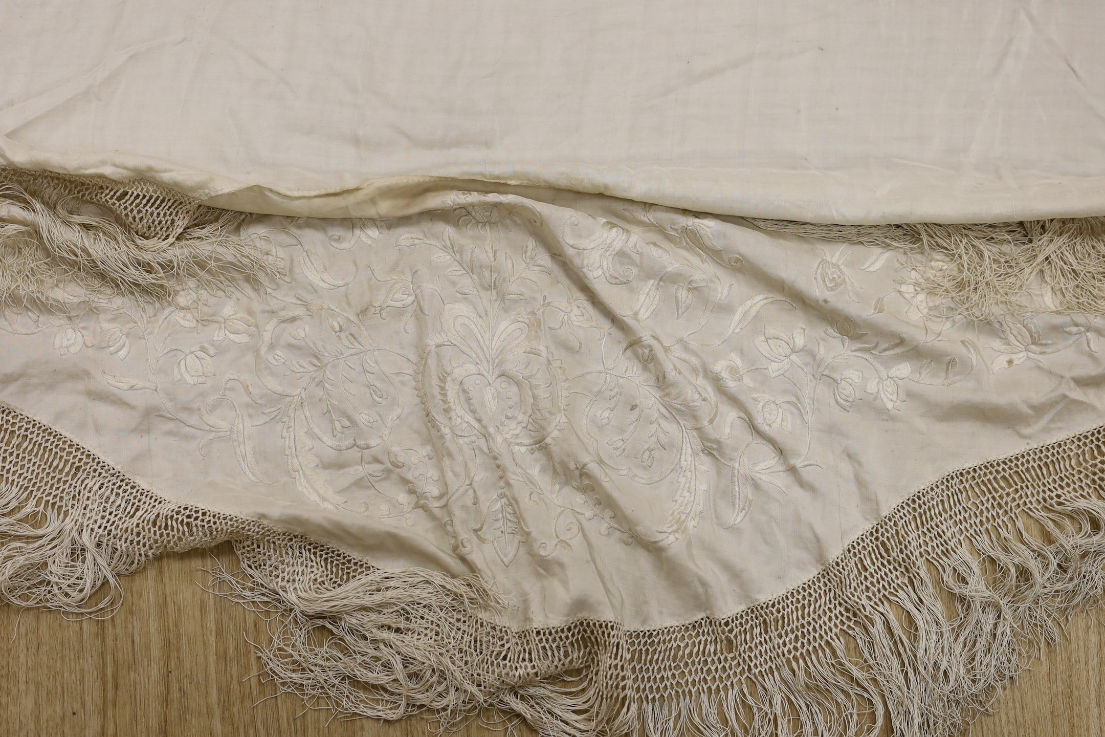 A late 19th/early 20th century Chinese cream silk shawl with cream silk embroidery and fringing, converted to a ladies cape